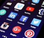 Close-up of a smartphone screen showing various social media app icons such as Facebook and Twitter.